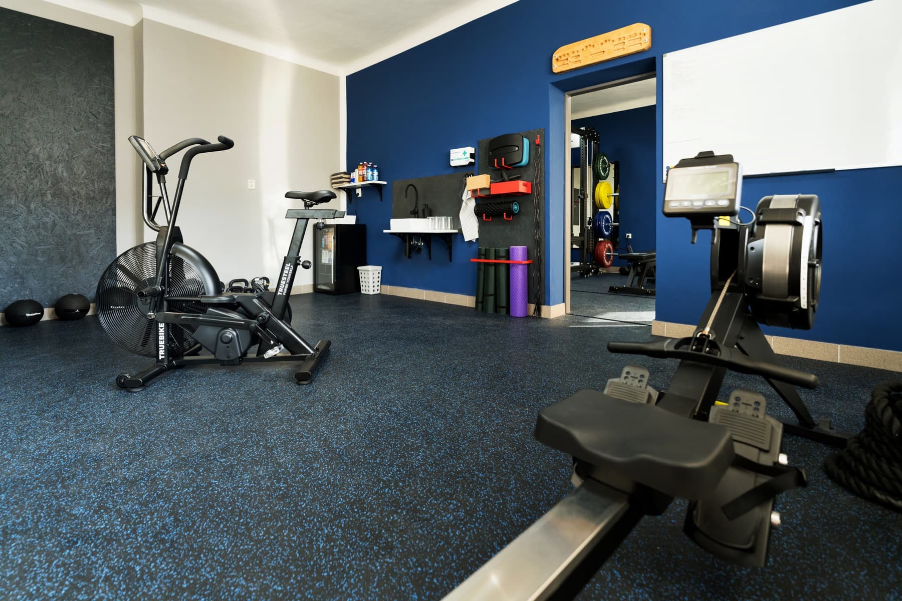 Kondiční část posilovny JimGym — air bike a veslařský trenažér