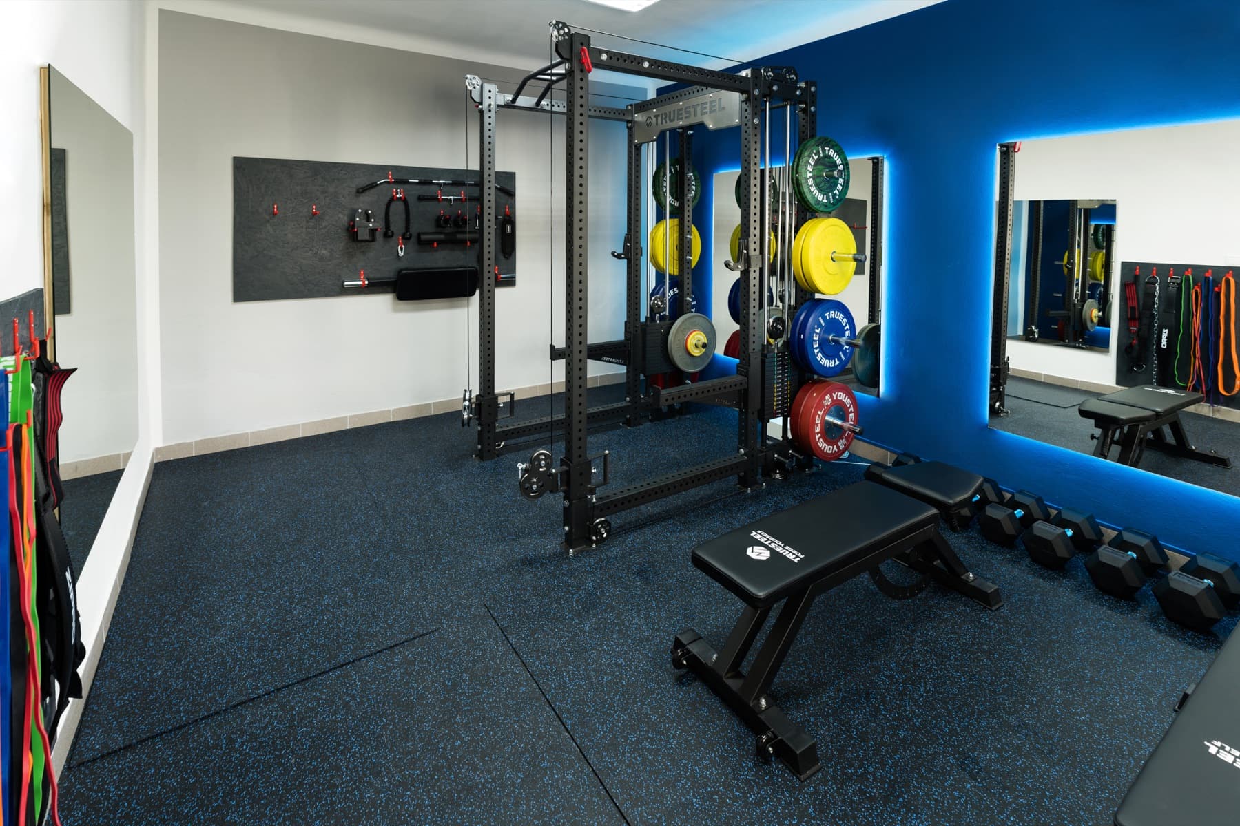 Privátní místnost JimGym s rackem, olympijskou osou a barevnými kotouči