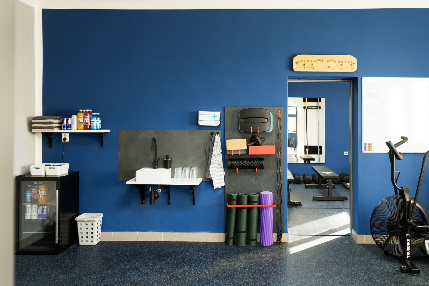 Zázemí JimGym — umyvadlo, ručníky, lednička s pitím a fyzio pomůcky